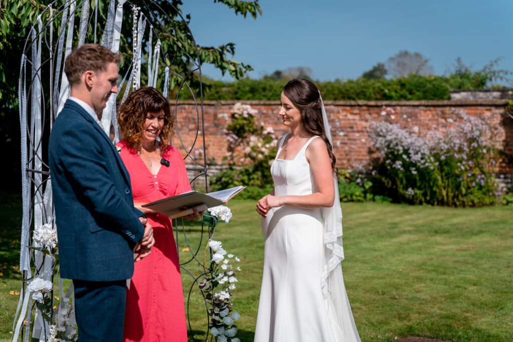 Ian Jeffrey Photography Bride and groom outdoors during a wedding ceremony with celebrant, Amy Lee, reading from a book